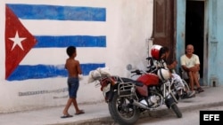 Un niño pasa junto a una pintura de la bandera cubana en una pared, en La Habana, Cuba. 