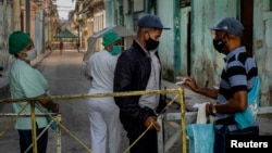 un policía verifica el documento de identidad de un residente en un barrio de La Habana en cuarentena por COVID-19. (AP Foto/Ramón Espinosa)