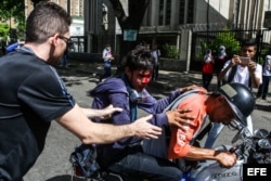 Un grupo de manifestantes ayuda a un compañero herido durante una marcha antigubernamental en Caracas.