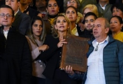 Flanqueada por el líder cívico de Santa Cruz Luis Fernando Camacho (a la derecha en la foto), la presidenta interina Jeanine Añez muestra una Biblia en la entrada del Palacio Quemado, residencia oficial del Ejecutivo boliviano (Foto: Aizar Raldes/AFP).