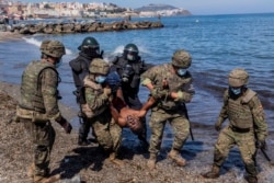 Soldados del ejército español expulsan a un migrante del enclave español de Ceuta, 18 de mayo de 2021.