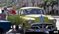 Varios turistas suben a un auto con la bandera de Estados Unidos