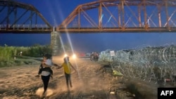 Migrantes caminan después de cruzar el Río Grande en la frontera entre Estados Unidos y México en Eagle Pass, Texas, el 22 de septiembre de 2023. (Foto de Paula RAMON / AFP)