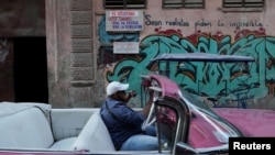 Un hombre pasa en su carro por una calle donde hay un cartel que invita a votar en las próximas elecciones legislativas del 26 de marzo. (REUTERS/Alexandre Meneghini).