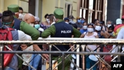 Policías controlando la población en una cola para conseguir alimentos.