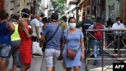 Policías controlan una fila de personas que espera para comprar alimentos en un mercado de La Habana, el 12 de abril del 2020.