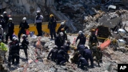 Rescatistas trabajan sobre los escombros de la parte del edificio residencial Champlain Towers South caído, donde hay decenas de desaparecidos a una semana de la catástrofe, en Surfside, Florida. (AP Foto/Mark Humphrey)