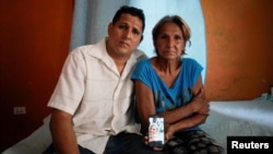 Alberto Betancourt y su madre Mayra Pérez posan con una foto de su hermana Daylin Betancourt, detenida por la policía durante una protesta, en La Habana, Cuba, el 19 de julio de 2021. Fotografía tomada el 19 de julio de 2021. REUTERS / Alexandre Meneghini