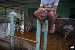 Varias personas en un portal inundado tras el paso del huracán Helene en Guanimar, provincia de Artemisa, Cuba, el miércoles 25 de septiembre de 2024. (Foto AP/Ramon Espinosa)