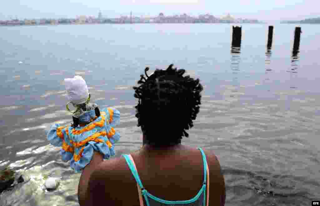 Una mujer reza frente al mar antes de participar, junto a cientos de personas en la procesión de la Virgen de Regla, en Cuba.