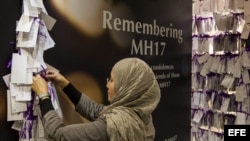 Una mujer cuelga un mensaje en homenaje a los pasajeros y la tripulación del vuelo MH17 de Malaysia Airlines en un centro comercial en Kuala Lumpur (Malasia)