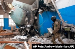 Un soldado ucraniano pasa junto a una pieza de la cola de un bombardero Su-34 ruso sobre un edificio dañado en Járkiv, Ucrania, el 8 de marzo de 2022.