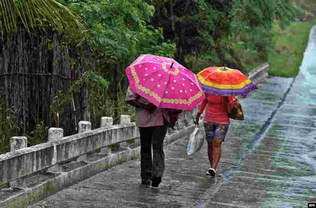 Dos personas caminan bajo la lluvia hoy, martes 04 de octubre, en la ciudad de Baracoa, en Guantánamo.