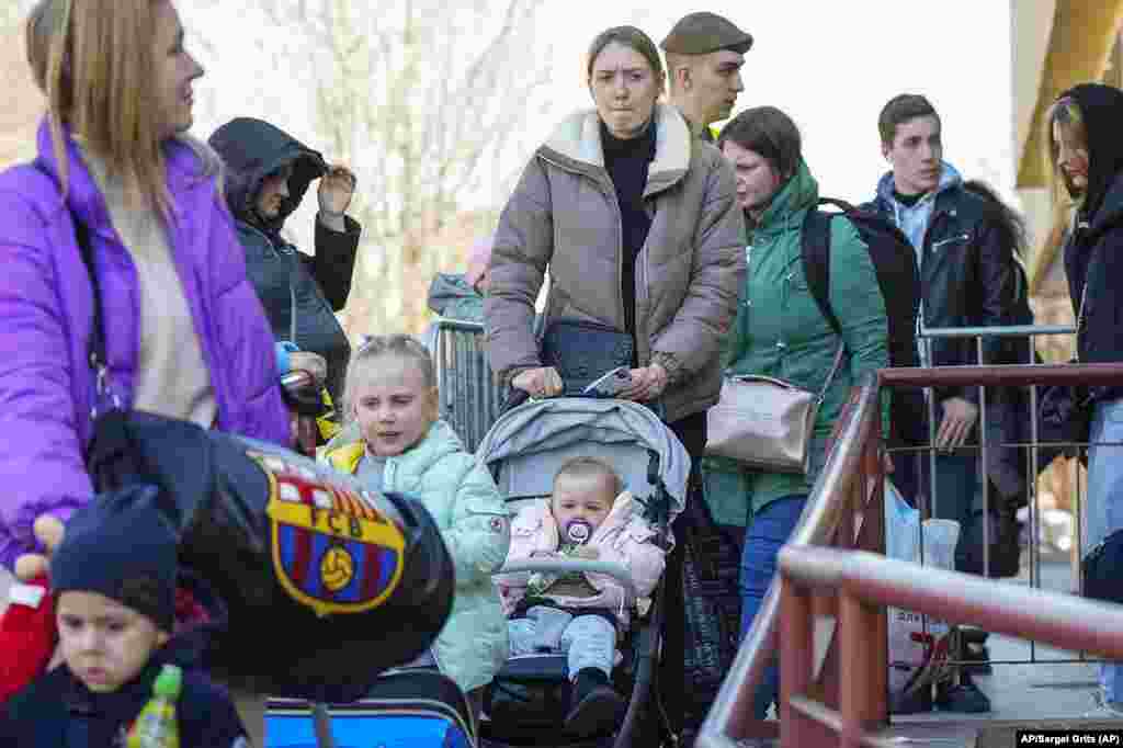 Refugiados con niños caminan en la vecina ciudad de Przemysl, Polonia, después de huir de la guerra en Ucrania. Foto: AP/Sergei Grits.