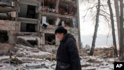 Una mujer pasa frente a un edificio dañado por los bombardeos rusos, el domingo 13 de marzo de 2022, en Járkiv, Ucrania. (AP Foto/Andrew Marienko)