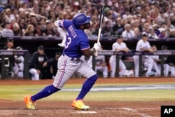 Adolis García, de los Rangers de Texas, se agarra el lado izquierdo después de su swing durante la octava entrada en el Juego 3 de la Serie Mundial de béisbol contra los Diamondbacks de Arizona el lunes 30 de octubre de 2023, en Phoenix. (AP Photo/Brynn Anderson)