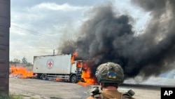 Un agente de policía observa un vehículo de la Cruz Roja en llamas que fue destruido en un ataque ruso en la región de Donetsk el jueves 12 de septiembre de 2024. (Policía de la Región de Donetsk vía AP)