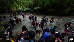 Migrantes cruzan un río durante su viaje a través del Tapón del Darién desde Colombia hacia Panamá, con la esperanza de llegar a Estados Unidos, el 15 de octubre de 2022. (AP/Fernando Vergara, Archivo)