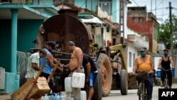 Vecinos recogen agua de una pipa la mañana del martes en un barrio de San Antonio de los Baños, en la provincia de Artemisa. (Yamil Lage/AFP).