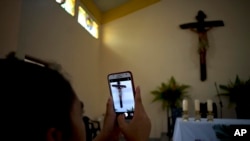 FOTO ARCHIVO. Un feligrés toma una fotografía del crucifijo sobre el altar en la Iglesia Sagrado Corazón de Jesús, en Sandino, Cuba. (Foto AP/Ramon Espinosa)