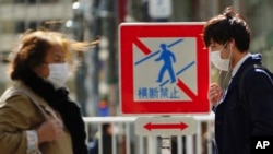 Peatones con mascarillas en una calle el jueves 5 de marzo de 2020 en Tokio. (AP Foto/Eugene Hoshiko)