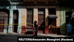 Una mujer pasa frente a varias casas en cuarentena por COVID-19 en un barrio de La Habana. REUTERS/Alexandre Meneghini